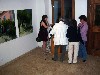 Lyudmila speaking to a group at the opening. Korbely&rsquo;s paintings are part of the photo.