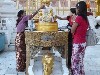 A devotee pours water over a Buddha statue at the planetary post for her day of birth
