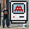 Shrinker by Space Invader with artist in mask next to piece