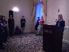 Addressing the audience at conference reception. Mary Sherman in the back ground, standing near the wall.