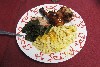 A serving of chicken with sides of mac and cheese as well as collard greens. 